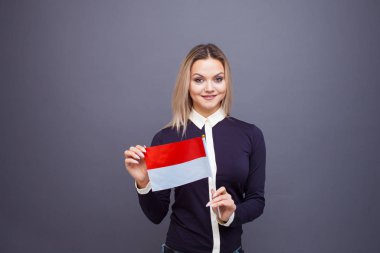 Göçmenlik ve yabancı dil eğitimi, konsept. Elinde Monako bayrağı olan gülümseyen genç bir kadın..