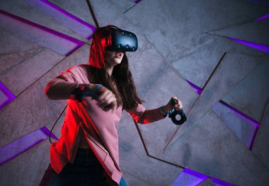 Kılıç kullan. Sanal kasklı genç bir kadın, sanal kılıçların kolları gibi her iki elinde de kontrolörler kullanır..