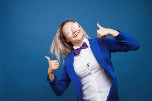 Divertida dama de negocios con chaqueta azul y pajarita púrpura. salta de alegría y da un pulgar hacia arriba . — Foto de Stock