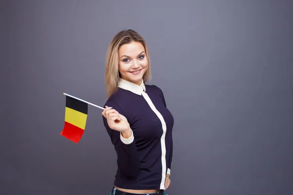 Invandring och studier av främmande språk, begrepp. En ung leende kvinna med en belgisk flagga i handen. — Stockfoto