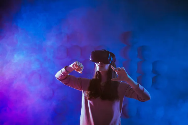 Uma jovem encantada em óculos de realidade virtual, contra o fundo futurista obter experiência no espaço virtual . — Fotografia de Stock
