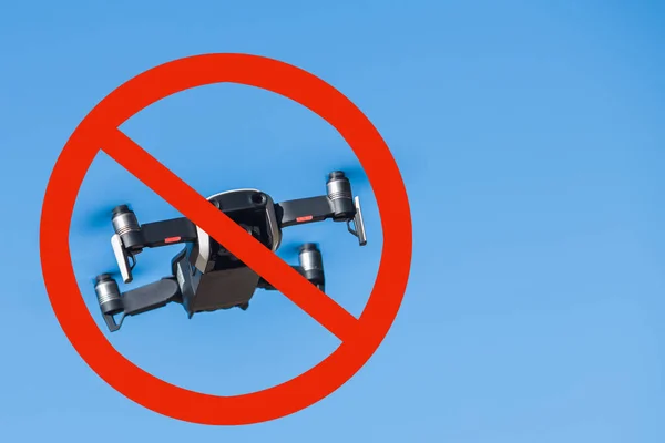 I droni sono proibiti. Drone a quattro eliche che vola in natura contro il cielo blu. Allegato al cartello rosso di divieto . — Foto Stock