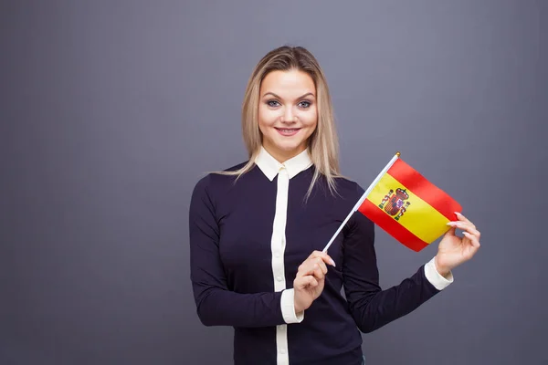 移民与外语学习,概念.一个年轻的微笑的女人手里拿着西班牙国旗. — 图库照片