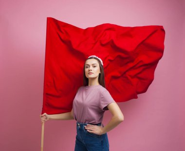 Aktivist ve devrimci, pembe arka planda kırmızı bayrağı olan genç bir kadın..