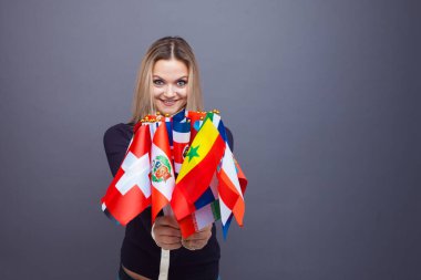 Dünyanın farklı ülkelerinden bayrakları olan neşeli genç bir kadın.