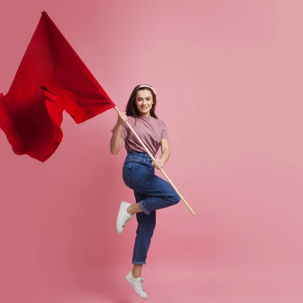 운동가이자 혁명적 인 젊은 여성, 핑크 색 배경에 빨간 깃발을 쓴 여성. — 스톡 사진
