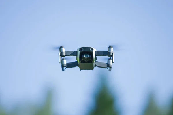 Drone de cuatro hélices volando en la naturaleza contra el cielo azul. La maniobra . —  Fotos de Stock