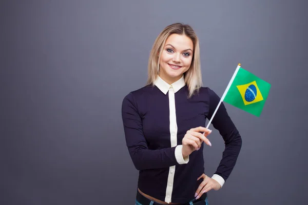 Immigratie en de studie van vreemde talen, concept. Een jonge glimlachende vrouw met een Braziliaanse vlag in haar hand. — Stockfoto