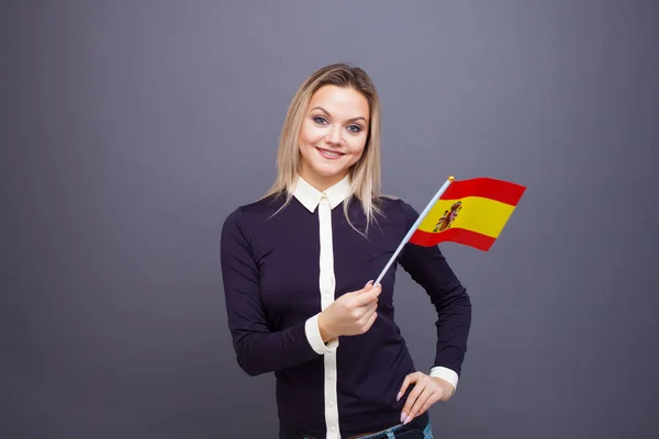移民与外语学习,概念.一个年轻的微笑的女人手里拿着西班牙国旗. — 图库照片