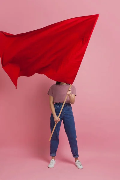 Молодая и красивая девушка с красным флагом на розовом фоне. Социально активная женщина, протестующая и борющаяся за права — стоковое фото