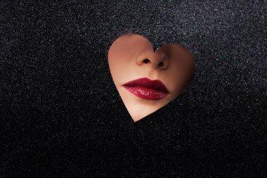 Sexy women's lips with red lipstick in a heart-shaped cutout.