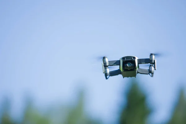 Drone de cuatro hélices volando en la naturaleza contra el cielo azul. La maniobra . —  Fotos de Stock
