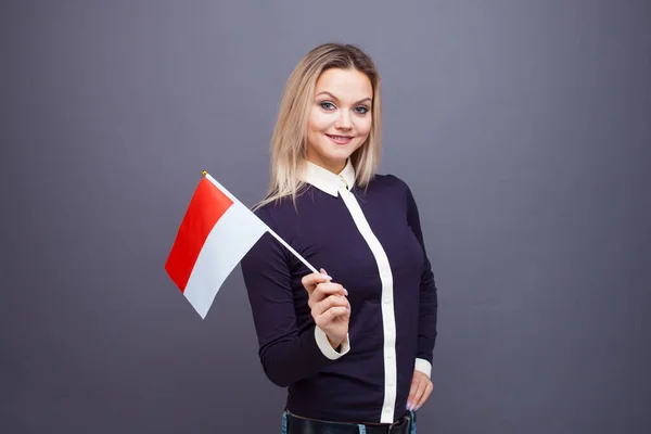 Einwanderung und Fremdsprachenstudium, Konzept. Eine junge lächelnde Frau mit einer Monaco-Fahne in der Hand. — Stockfoto