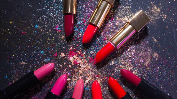 Cosmetics and beauty industry, a set of lipsticks on a background of loose powder and eye shadow, — Stock Fotó