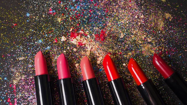 Cosmetics and beauty industry, a set of lipsticks on a background of loose powder and eye shadow, — Stock Fotó