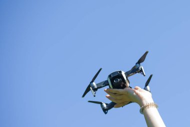 Dişi eller mavi gökyüzünün arka planında bir dron tutuyor. Bir İHA yakala.