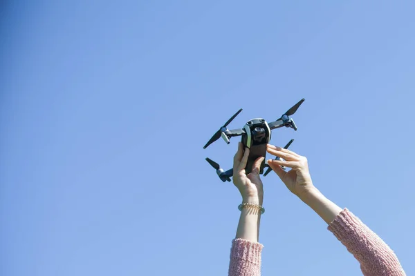 Le mani femminili tengono un drone su uno sfondo di cielo blu. Cattura un drone . — Foto Stock