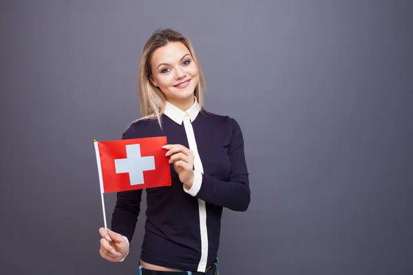 Inmigración y el estudio de lenguas extranjeras, concepto. Una joven sonriente con una bandera de Suiza en la mano. — Foto de Stock