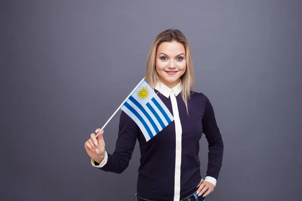 Immigration and the study of foreign languages, concept. A young smiling woman with a Uruguay flag in her hand. — Stock Photo, Image