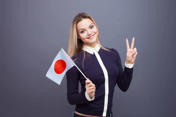 stock image Immigration and the study of foreign languages, concept. A young smiling woman with a Japan flag in her hand.