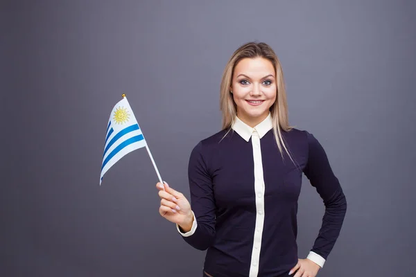 Inmigración y el estudio de lenguas extranjeras, concepto. Una joven sonriente con una bandera de Uruguay en la mano. — Foto de Stock