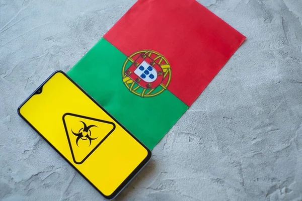 Επιδημιολογική κατάσταση στη χώρα Πορτογαλία. Σημαία και smartphone με ειδήσεις και σύμβολο βιολογικού κινδύνου. — Φωτογραφία Αρχείου