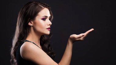 Şık ve parlak bir akşam görüntüsü olan lüks genç kadın avucunun içinde bir şey tutuyor.,