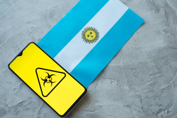 Situazione epidemiologica nel paese Argentina. Bandiera e smartphone con notizie e simbolo di rischio biologico . — Foto Stock