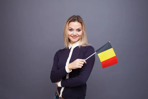Einwanderung und Fremdsprachenstudium, Konzept. Eine junge lächelnde Frau mit einer belgischen Flagge in der Hand. — Stockfoto