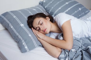Sağlıklı geceler yatakta uyuyun, güzel esmer kadın uyuyor.
