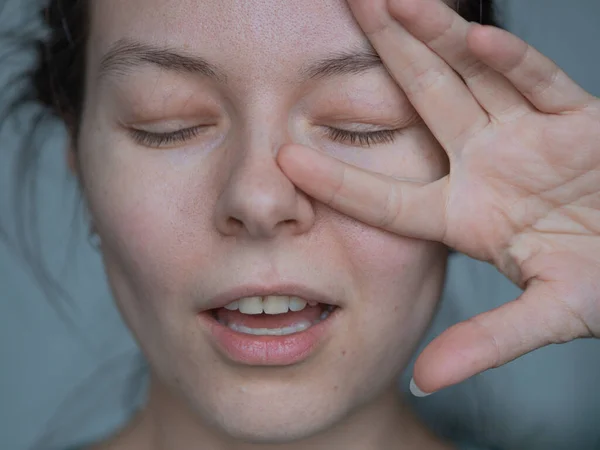 Heureuse jeune femme rit et fait un geste de la main, deux doigts en l'air. Super gros plan — Photo