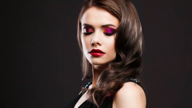 Gorgeous young brunette in a chic evening look. Scarlet lips and eye shadow,