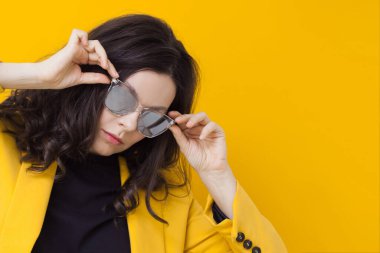 Parlak sarı ceketli ve aynalı güneş gözlüklü şık ve cesur bir esmer..