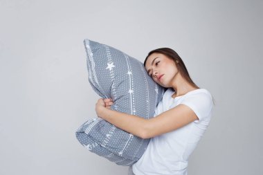 Uyku ve uykusuzluk, genç bir kadın yastığa sarılıyor ve ayakta uyuyor.