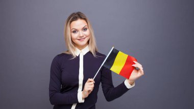 Göçmenlik ve yabancı dil eğitimi, konsept. Elinde Belçika bayrağı olan gülümseyen genç bir kadın..