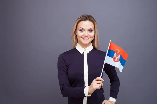 Immigration and the study of foreign languages, concept. A young smiling woman with a Serbia flag in her hand. — Stock Photo, Image