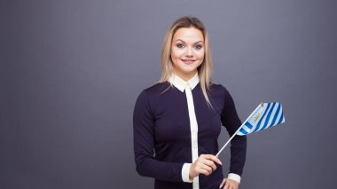 Göçmenlik ve yabancı dil eğitimi, konsept. Elinde Uruguay bayrağı olan gülümseyen genç bir kadın..