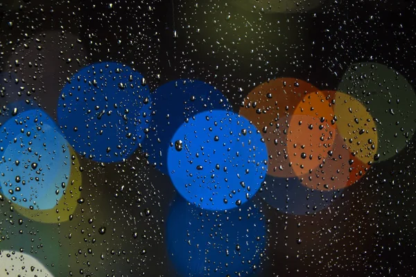 ฝนตกบนหน้าต่างด้วยไฟจราจร bokeh — ภาพถ่ายสต็อก