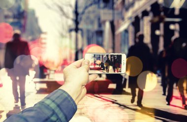 Akıllı telefon kullanan adam şehirde insanlar fotoğrafını kalabalık sokakta çekin.