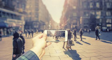 Akıllı telefon kullanan adam şehirde insanlar fotoğrafını kalabalık sokakta çekin.