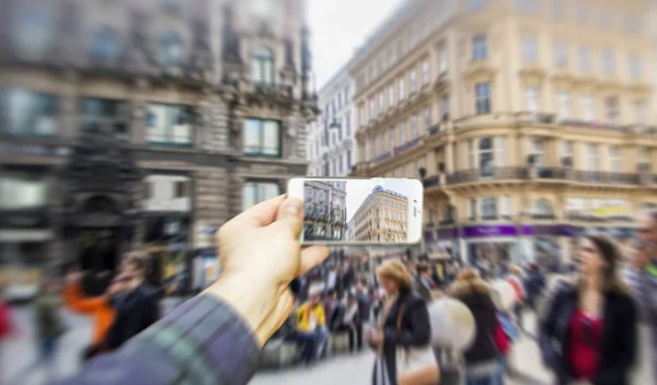 Homem usando telefone inteligente tirar uma foto de pessoas da cidade na rua lotada — Fotografia de Stock