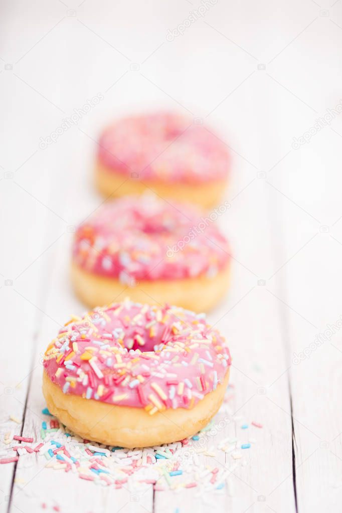 Pink donuts with sparkles  on wooden table 
