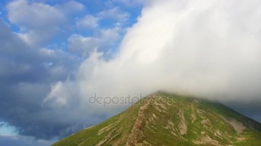 Düşük güneş ışınlarının en yüksek dağ Zirvesi bulutlar kaplı. Zaman atlamalı.