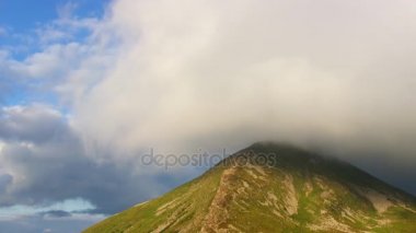 Düşük güneş ışınlarının en yüksek dağ Zirvesi bulutlar kaplı. Zaman atlamalı.