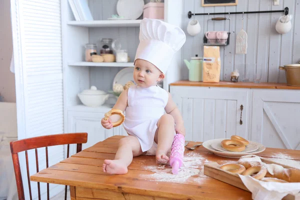Baby cooking homemade cakes. Early spring, Easter and a little girl in the chef's costume in the kitchen bakes bread and biscuits. The girl got dirty with flour. Mom's helper — Stock Photo, Image