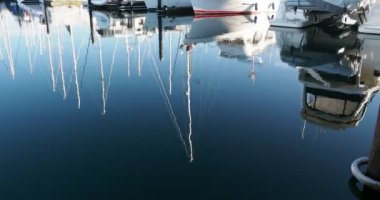 Reflections of the yachts and their masts in the calm waters of the marina in Sidney BC