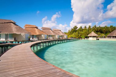 A view at the beach and waterhuts at tropical island, Maldives clipart