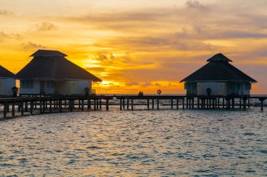Tropik adada gün batımı, su villaları tatil beldesi