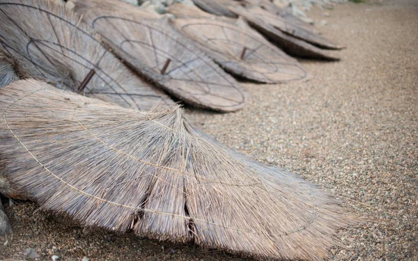 Roofs from beach umbrellas lie on an empty closed uninhabited beach — Stock Photo, Image