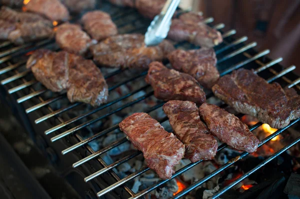 Kuchař připravuje šťavnaté steaky z mramorované maso na grilu — Stock fotografie